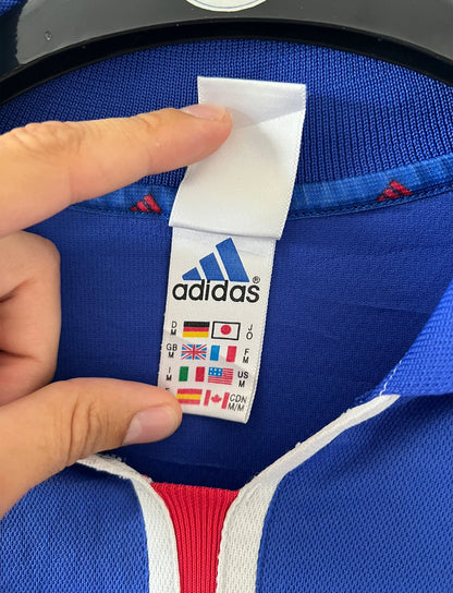 Maillot de foot vintage domicile bleu de l'équipe de france 2000. On peut retrouver l'équipementier Adidas et le flocage de Zinedine Zidane. Il s'agit d'un maillot authentique d'époque.