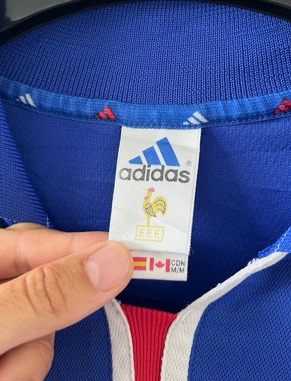 Maillot de foot vintage domicile bleu de l'équipe de france 2000. On peut retrouver l'équipementier Adidas et le flocage de Zinedine Zidane. Il s'agit d'un maillot authentique d'époque.