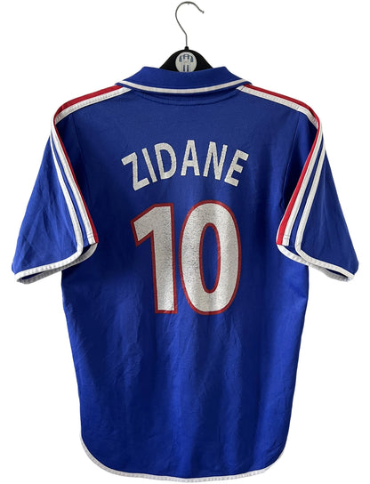 Maillot de foot vintage domicile bleu de l'équipe de france 2000. On peut retrouver l'équipementier Adidas et le flocage de Zinedine Zidane. Il s'agit d'un maillot authentique d'époque.