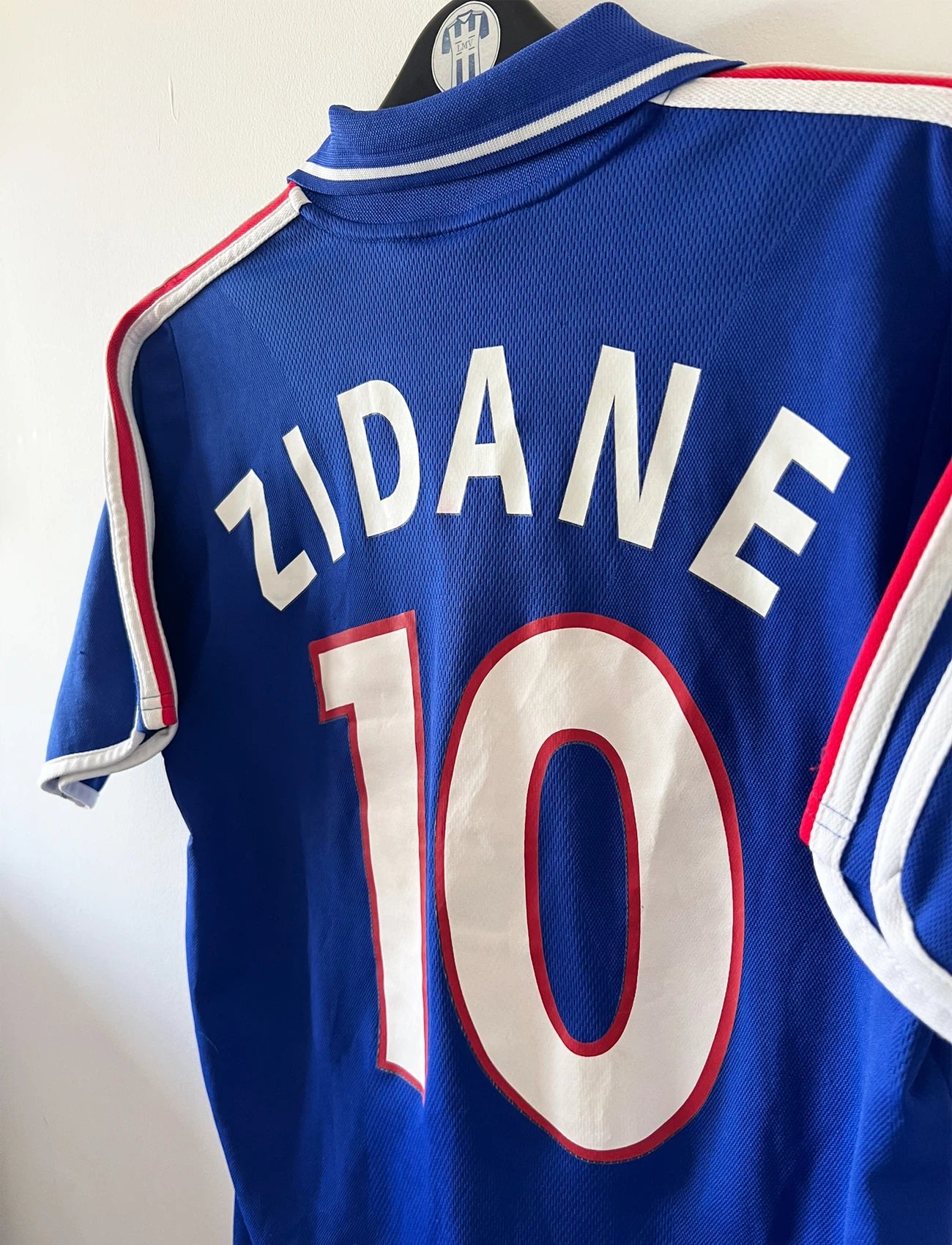 Maillot de foot vintage domicile bleu de l'Equipe de France 2000. On peut retrouver l'équipementier Adidas. Le maillot est floqué du numéro 10 Zinedine Zidane. Il s'agit d'un maillot authentique d'époque.