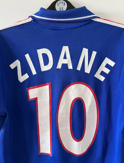 Maillot de foot vintage domicile bleu de l'Equipe de France 2000. On peut retrouver l'équipementier Adidas. Le maillot est floqué du numéro 10 Zinedine Zidane. Il s'agit d'un maillot authentique d'époque.