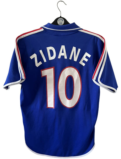 Maillot de foot vintage domicile bleu de l'Equipe de France 2000. On peut retrouver l'équipementier Adidas. Le maillot est floqué du numéro 10 Zinedine Zidane. Il s'agit d'un maillot authentique d'époque.