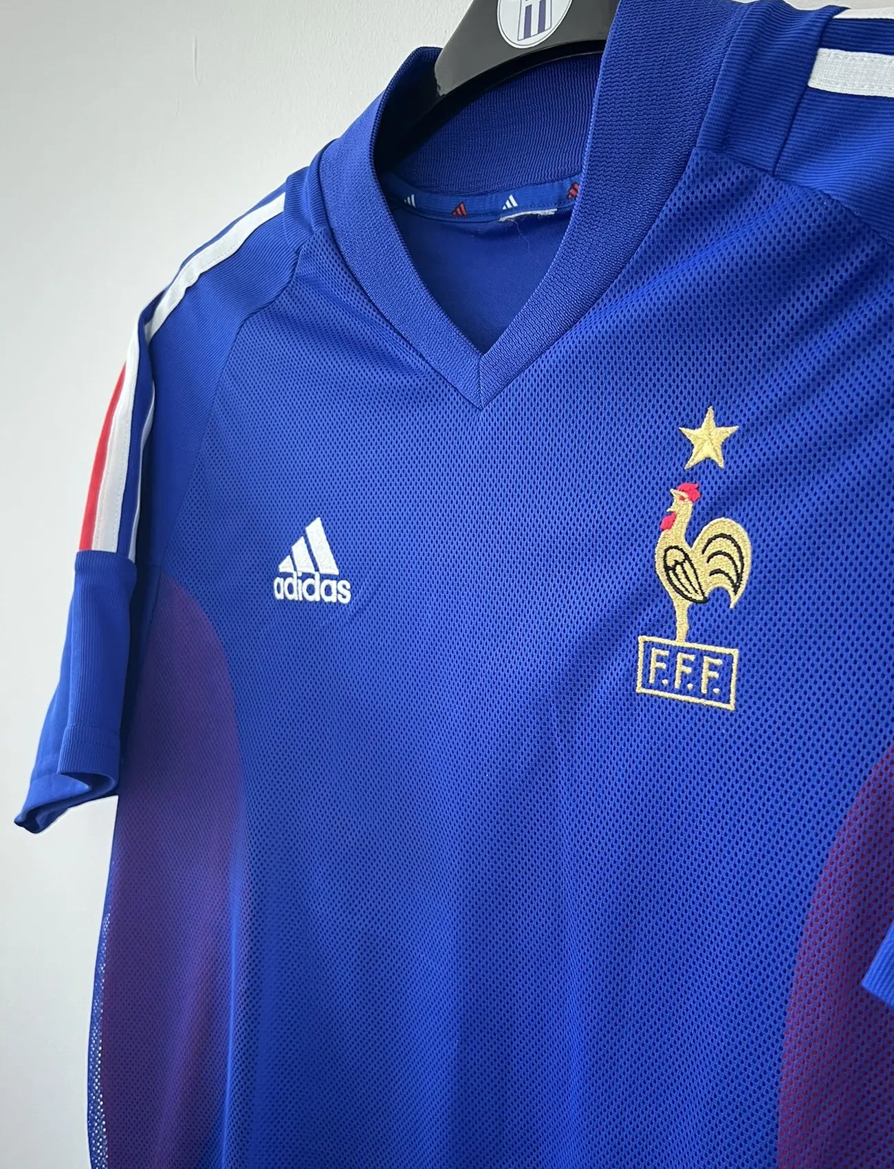 Maillot de foot vintage domicile de l'équipe de france 2002. Le maillot est de couleur bleu blanc et rouge. On peut retrouver l'équipementier adidas. Le maillot est floqué du numéro 10 Zinedine Zidane. Il s'agit d'un maillot authentique d'époque comportant les numéros 139531.