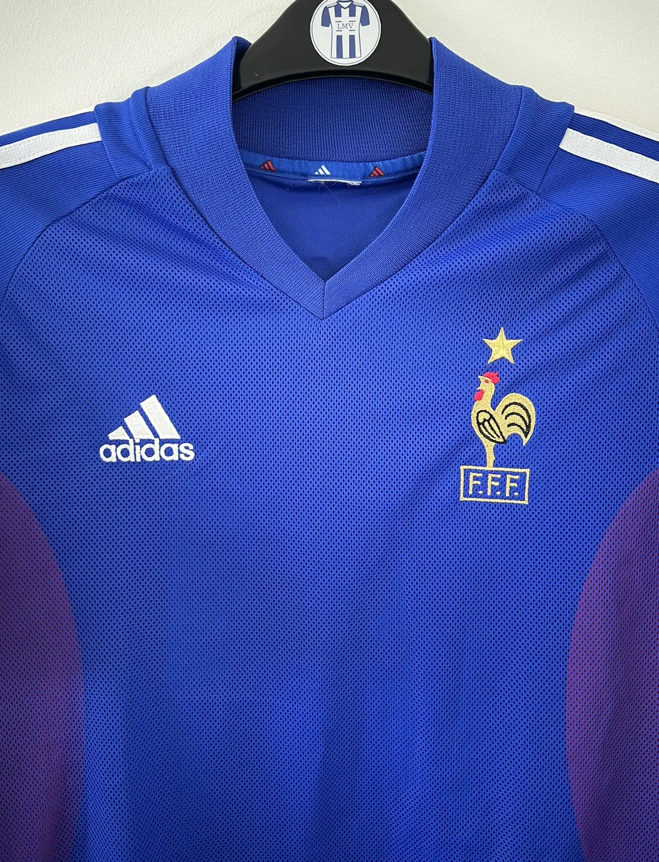 Maillot de foot vintage domicile de l'équipe de france 2002. Le maillot est de couleur bleu blanc et rouge. On peut retrouver l'équipementier adidas. Le maillot est floqué du numéro 10 Zinedine Zidane. Il s'agit d'un maillot authentique d'époque comportant les numéros 139531.