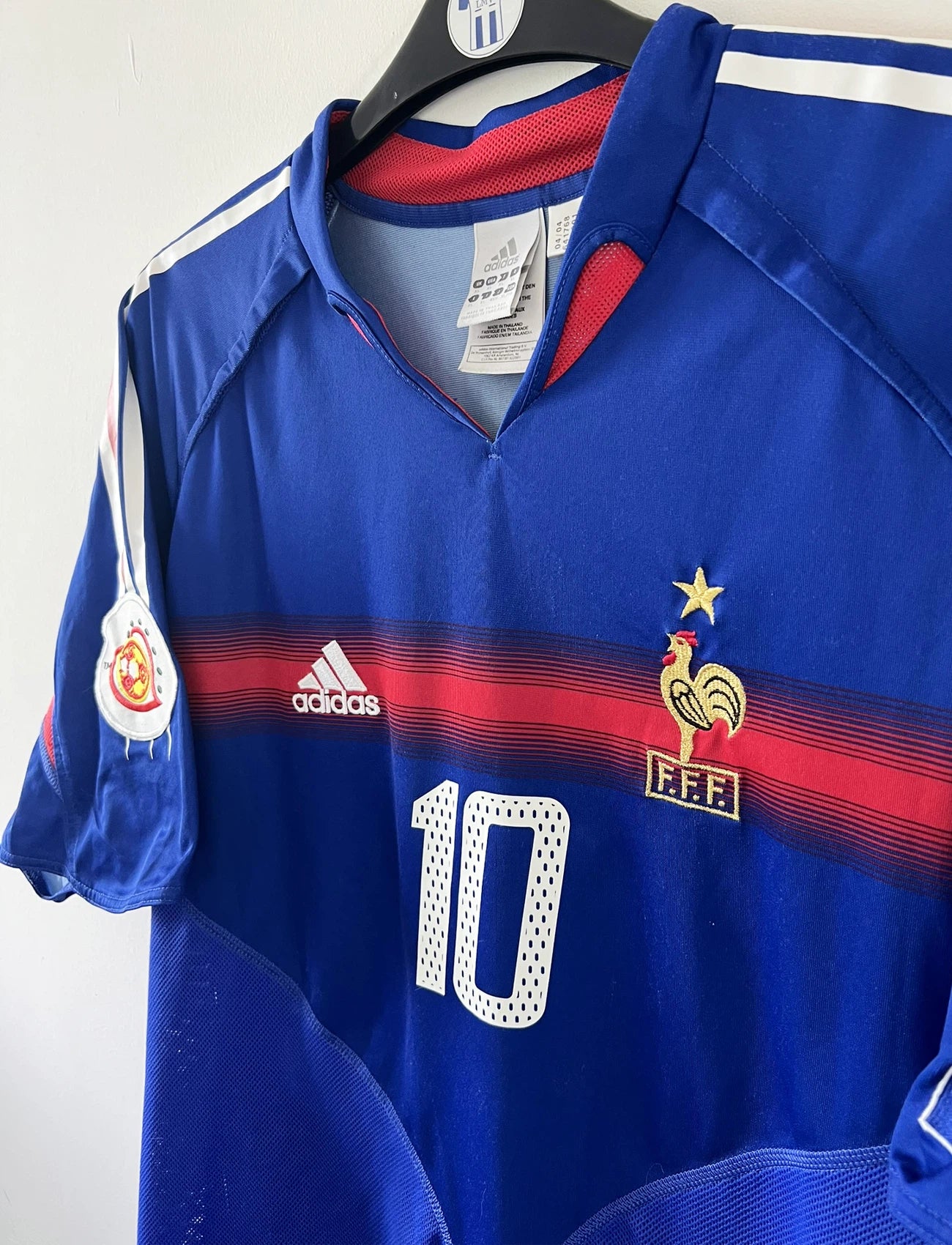 Maillot de foot vintage domicile bleu blanc et rouge de l'équipe de france 2004. On peut retrouver l'équipementier adidas. Il s'agit d'un maillot authentique d'époque comportant le numéro 641768