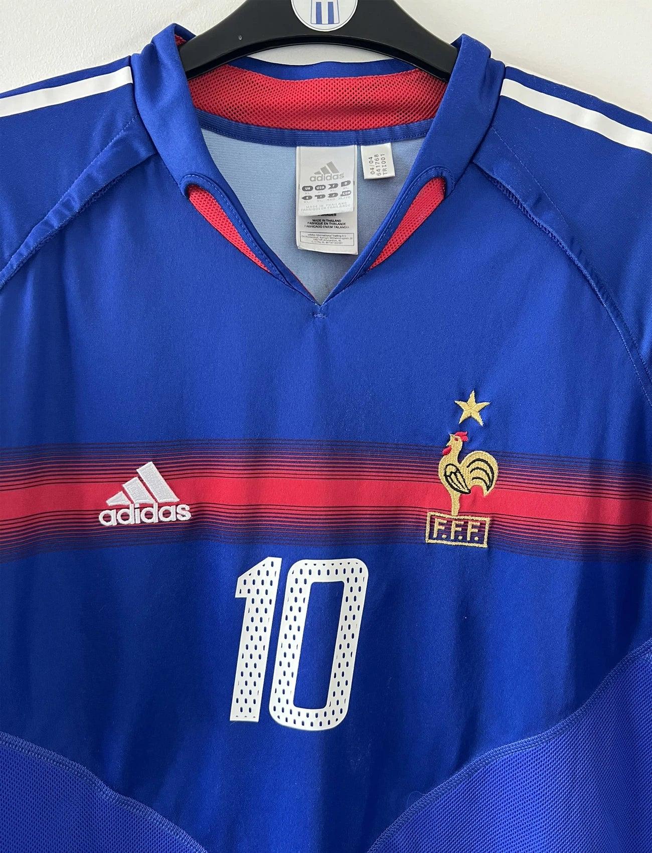 Maillot de foot vintage domicile bleu blanc et rouge de l'équipe de france 2004. On peut retrouver l'équipementier adidas. Il s'agit d'un maillot authentique d'époque comportant le numéro 641768