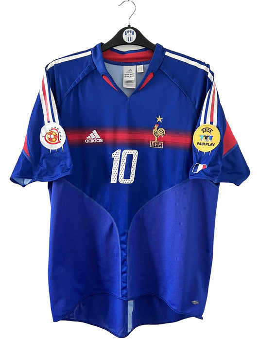 Maillot de foot vintage domicile bleu blanc et rouge de l'équipe de france 2004. On peut retrouver l'équipementier adidas. Il s'agit d'un maillot authentique d'époque comportant le numéro 641768