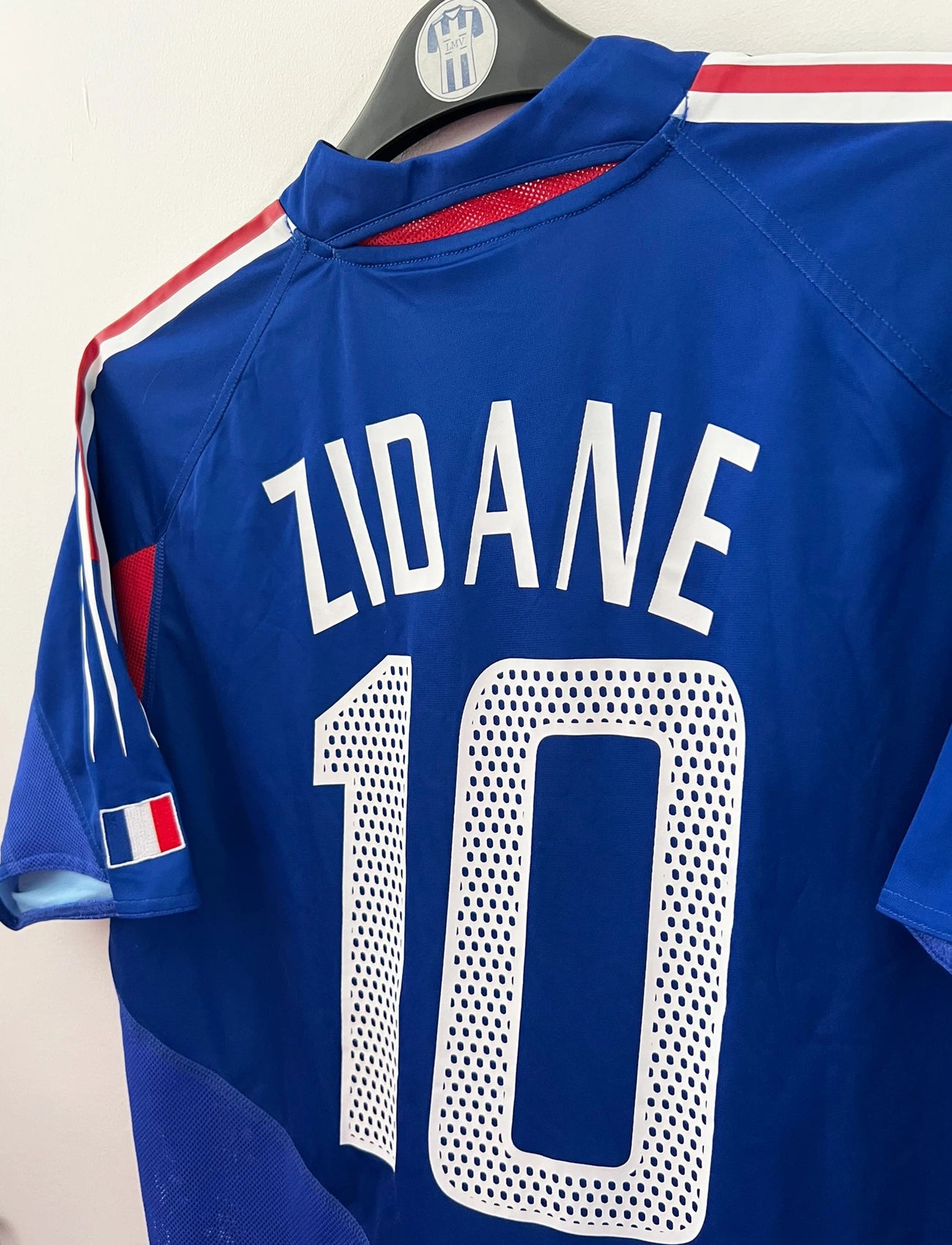 Maillot de foot vintage domicile bleu de l'équipe de france 2004. On peut retrouver l'équipementier Adidas. Le maillot est floqué du numéro 10 Zinedine Zidane. Il s'agit d'un maillot authentique d'époque.
