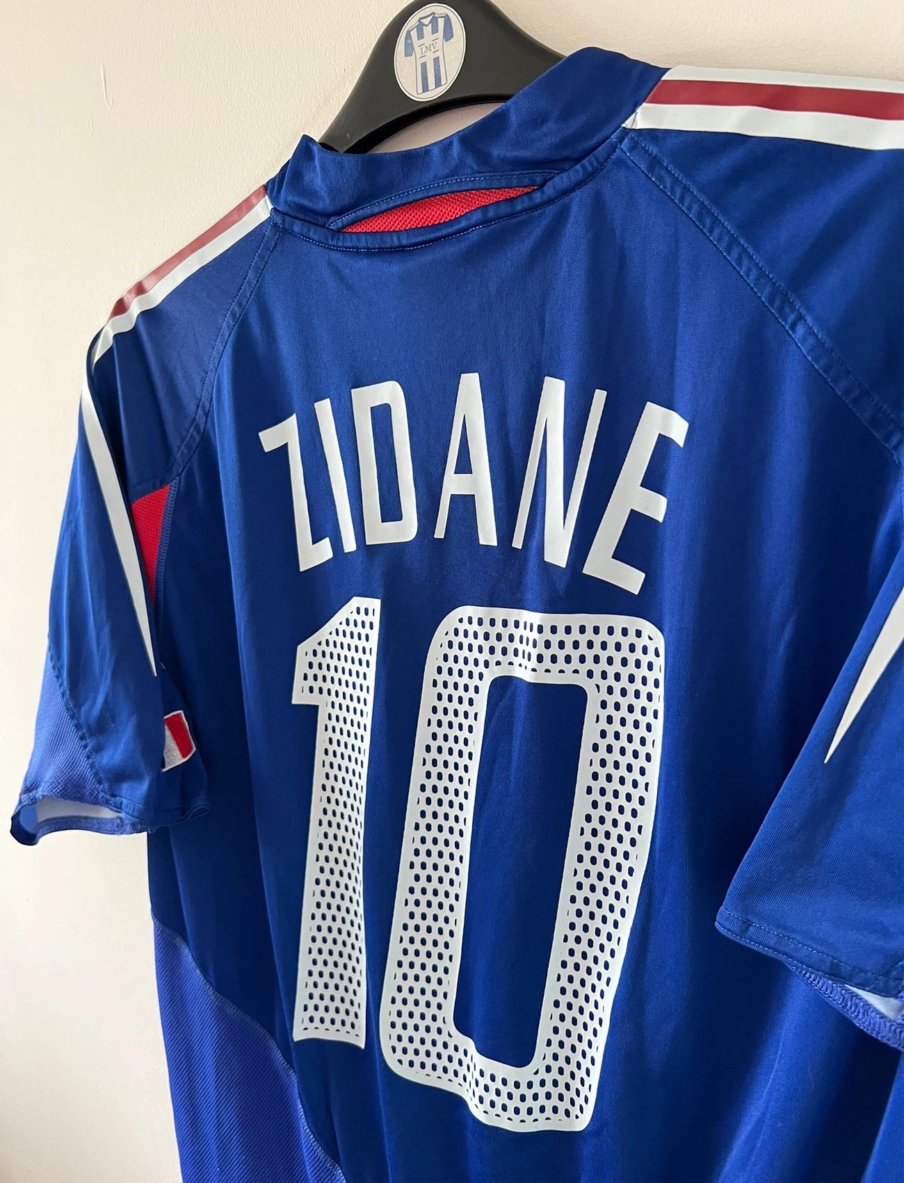 Maillot de foot vintage domicile bleu de l'Equipe de France 2004. On peut retrouver l'équipementier Adidas. Le maillot est floqué du numéro 10 Zinedine Zidane. Il s'agit d'un maillot authentique d'époque.