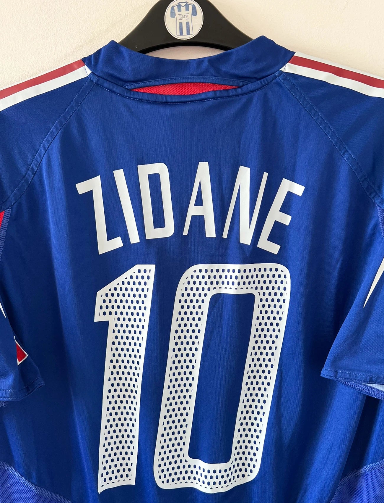 Maillot de foot vintage domicile bleu de l'Equipe de France 2004. On peut retrouver l'équipementier Adidas. Le maillot est floqué du numéro 10 Zinedine Zidane. Il s'agit d'un maillot authentique d'époque.