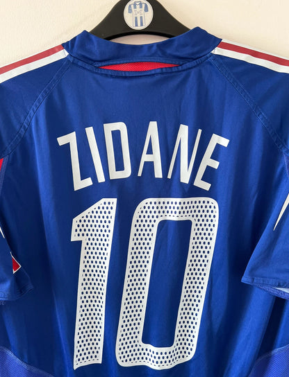 Maillot de foot vintage domicile bleu de l'Equipe de France 2004. On peut retrouver l'équipementier Adidas. Le maillot est floqué du numéro 10 Zinedine Zidane. Il s'agit d'un maillot authentique d'époque.
