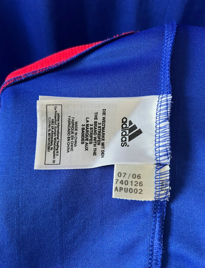 Maillot de foot vintage domicile bleu de l'équipe de france 2006. On peut retrouver l'équipementier Adidas. Il s'agit d'un maillot authentique d'époque.