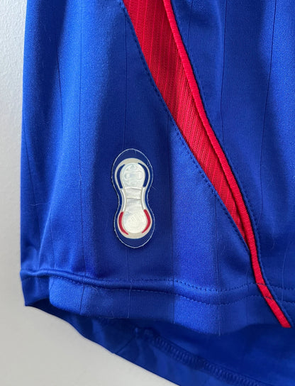 Maillot de foot vintage domicile bleu de l'équipe de france 2006. On peut retrouver l'équipementier Adidas. Il s'agit d'un maillot authentique d'époque.
