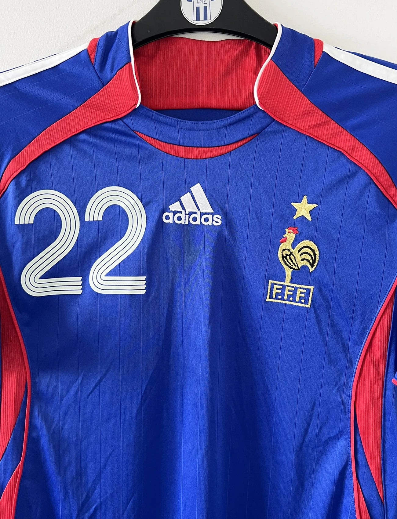 Maillot de foot vintage domicile de l'équipe de france 2006. On peut retrouver l'équipementier adidas. Le maillot est floqué du numéro 22 Franck Ribery. Il s'agit d'un maillot authentique d'époque comportant les numéros 740126