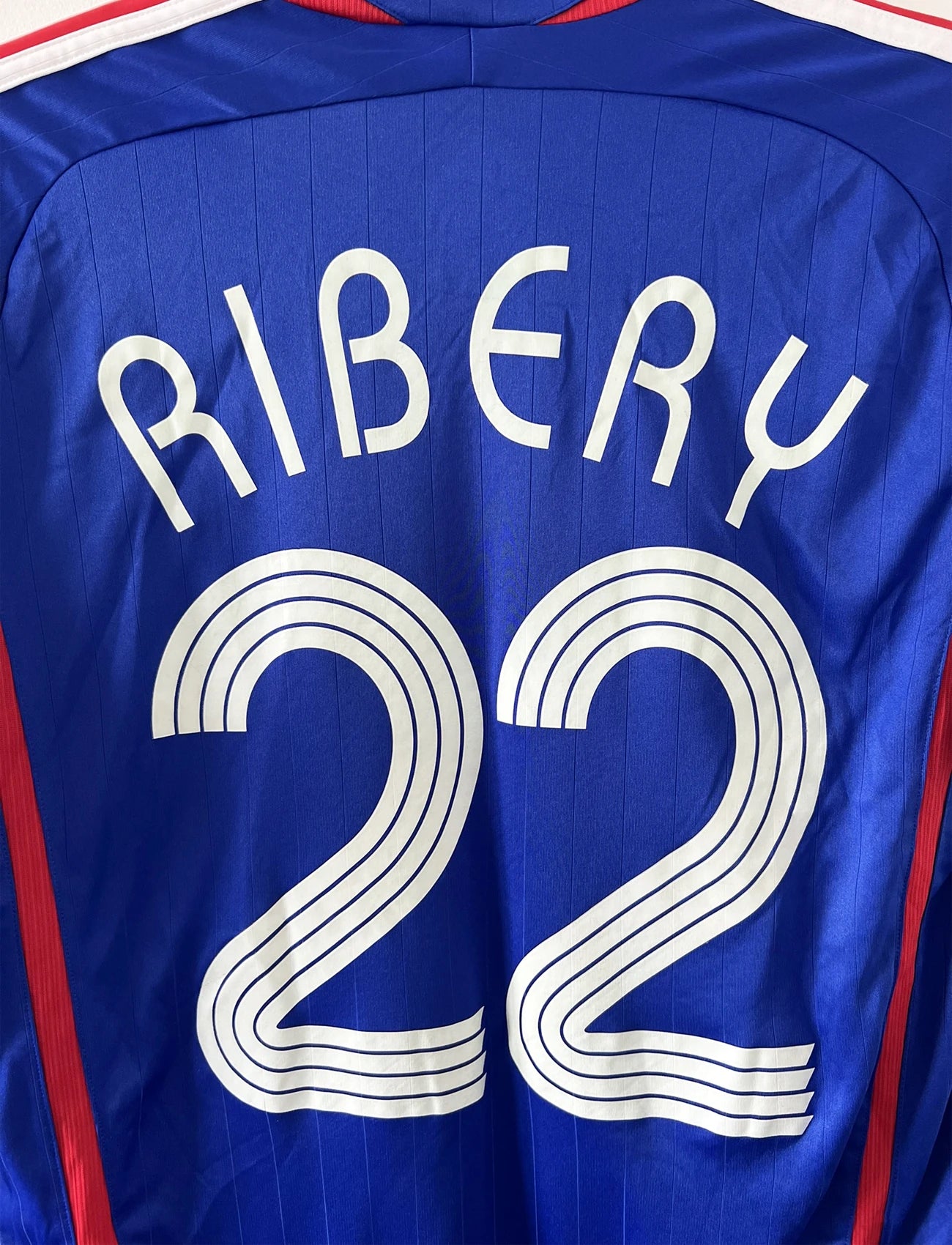 Maillot de foot vintage domicile de l'équipe de france 2006. On peut retrouver l'équipementier adidas. Le maillot est floqué du numéro 22 Franck Ribery. Il s'agit d'un maillot authentique d'époque comportant les numéros 740126