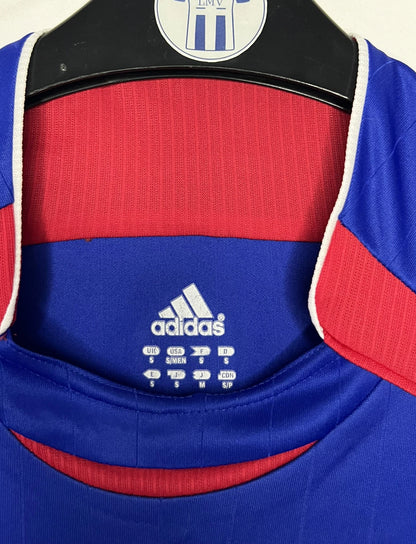 Maillot de foot vintage domicile bleu de l'équipe de france 2006. On peut retrouver l'équipementier Adidas. Le maillot est floqué du numéro 10 Zinedine Zidane. Il s'agit d'un maillot authentique d'époque comportant l'étiquette 740126.