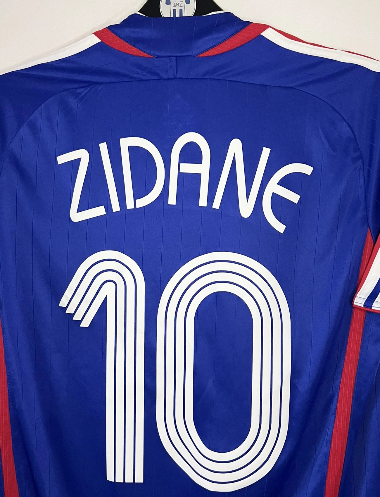 Maillot de foot vintage domicile bleu de l'équipe de france 2006. On peut retrouver l'équipementier Adidas. Le maillot est floqué du numéro 10 Zinedine Zidane. Il s'agit d'un maillot authentique d'époque comportant l'étiquette 740126.