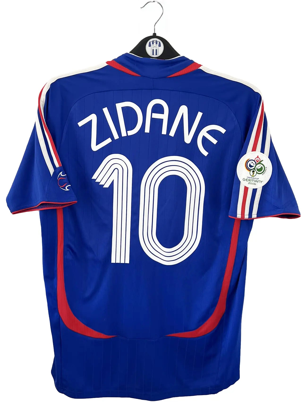 Maillot de foot vintage domicile bleu, blanc et rouge de l'équipe de france 2006. On peut retrouver l'équipementier adidas. Le maillot est floqué du numéro 10 Zinedine Zidane. Il s'agit d'un maillot authentique d'époque comportant l'étiquette 740126