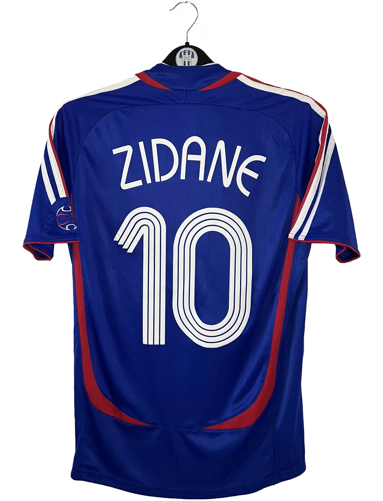 Maillot de foot vintage domicile bleu de l'équipe de france 2006. On peut retrouver l'équipementier Adidas. Le maillot est floqué du numéro 10 Zinedine Zidane. Il s'agit d'un maillot authentique d'époque comportant l'étiquette 740126.