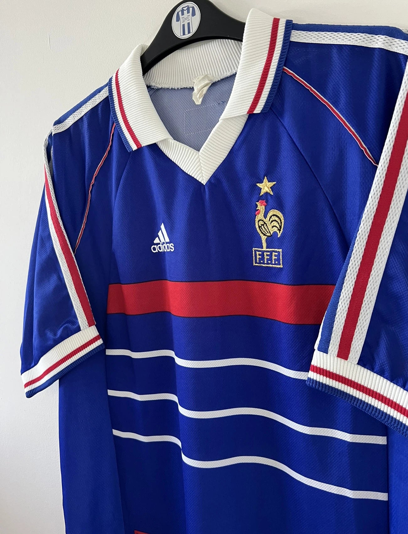 Maillot de foot vintage domicile bleu, blanc et rouge de l'équipe de france 1998. On peut retrouver l'équipementier adidas. Le maillot est floqué du numéro 17 Emmaunel Petit. Il s'agit d'un maillot authentique d'époque