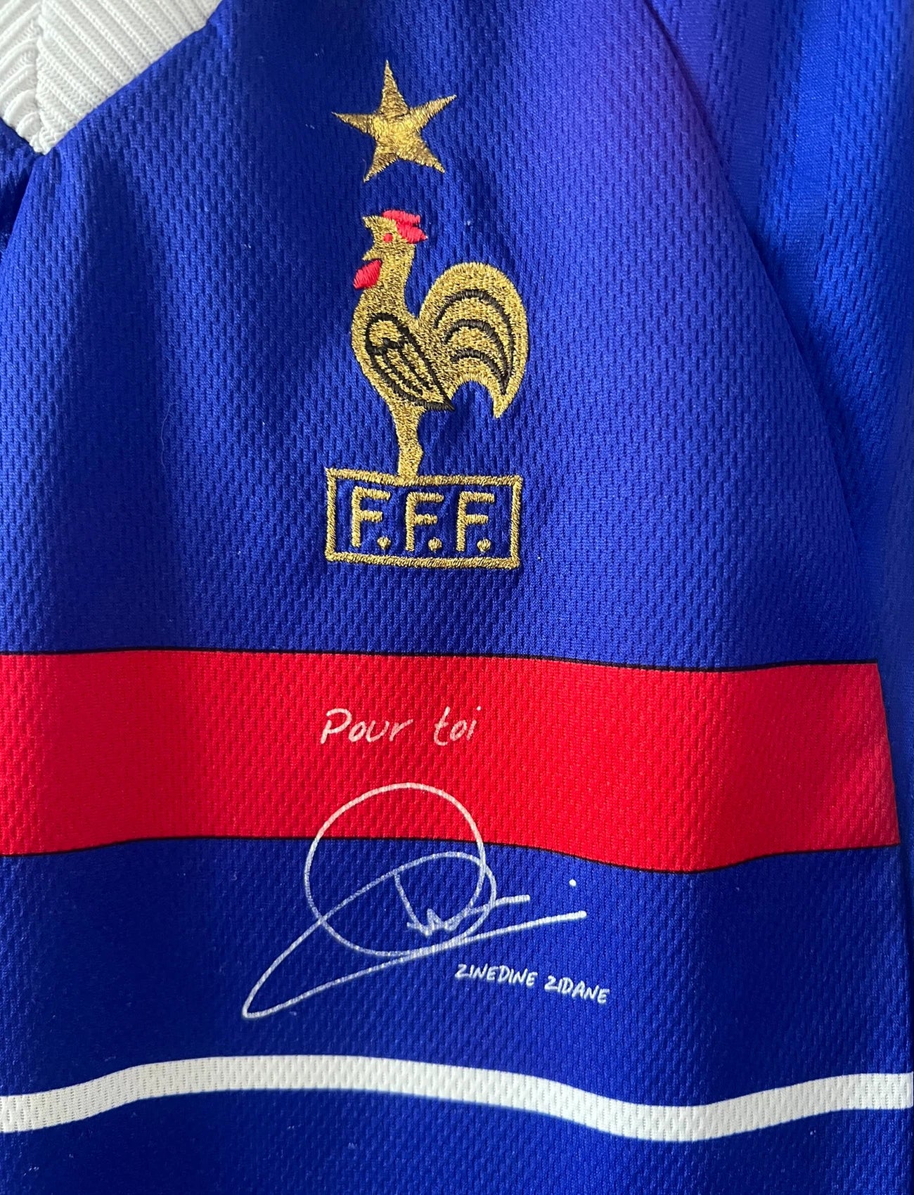 Maillot foot vintage domicile equipe de france 1998 bleu blanc et rouge. On peut retrouver l'équipementier adidas. Il s'agit d'un maillot authentique d'époque. Le maillot est floqué du numéro 10 Zinedine Zidane et comporte également sa signature avec la mention "pour toi Zinedine Zidane"