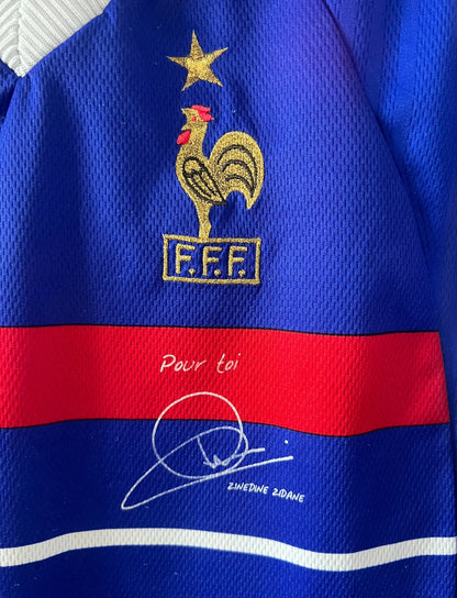 Maillot foot vintage domicile equipe de france 1998 bleu blanc et rouge. On peut retrouver l'équipementier adidas. Il s'agit d'un maillot authentique d'époque. Le maillot est floqué du numéro 10 Zinedine Zidane et comporte également sa signature avec la mention "pour toi Zinedine Zidane"