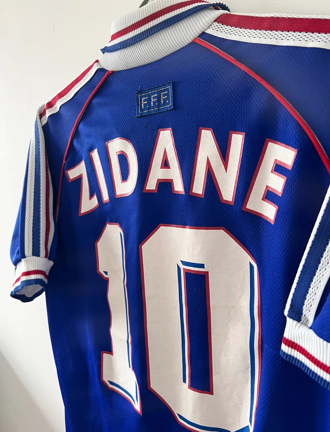 Maillot foot vintage domicile equipe de france 1998 bleu blanc et rouge. On peut retrouver l'équipementier adidas. Il s'agit d'un maillot authentique d'époque. Le maillot est floqué du numéro 10 Zinedine Zidane et comporte également sa signature avec la mention "pour toi Zinedine Zidane"
