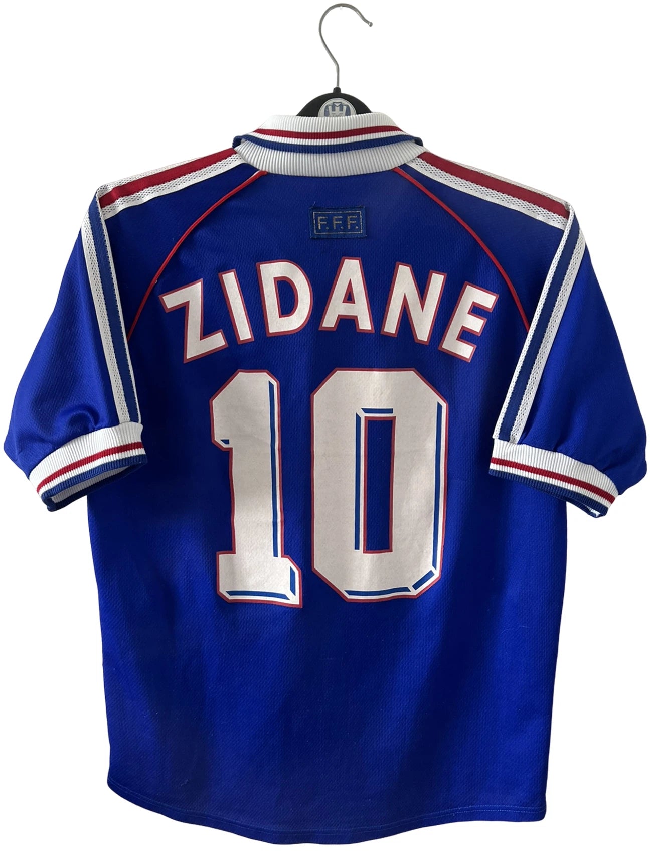 Maillot foot vintage domicile equipe de france 1998 bleu blanc et rouge. On peut retrouver l'équipementier adidas. Il s'agit d'un maillot authentique d'époque. Le maillot est floqué du numéro 10 Zinedine Zidane et comporte également sa signature avec la mention "pour toi Zinedine Zidane"