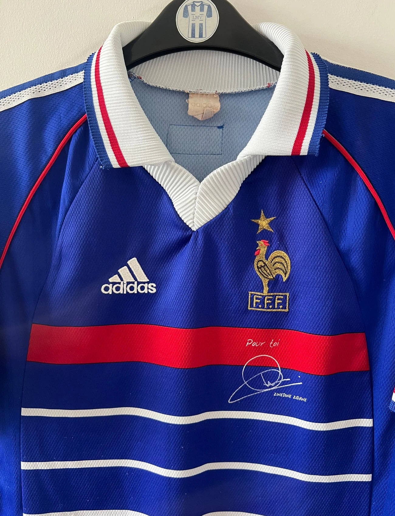 Maillot foot vintage domicile equipe de france 1998 bleu blanc et rouge. On peut retrouver l'équipementier adidas. Il s'agit d'un maillot authentique d'époque. Le maillot est floqué du numéro 10 Zinedine Zidane et comporte également sa signature avec la mention "pour toi Zinedine Zidane"