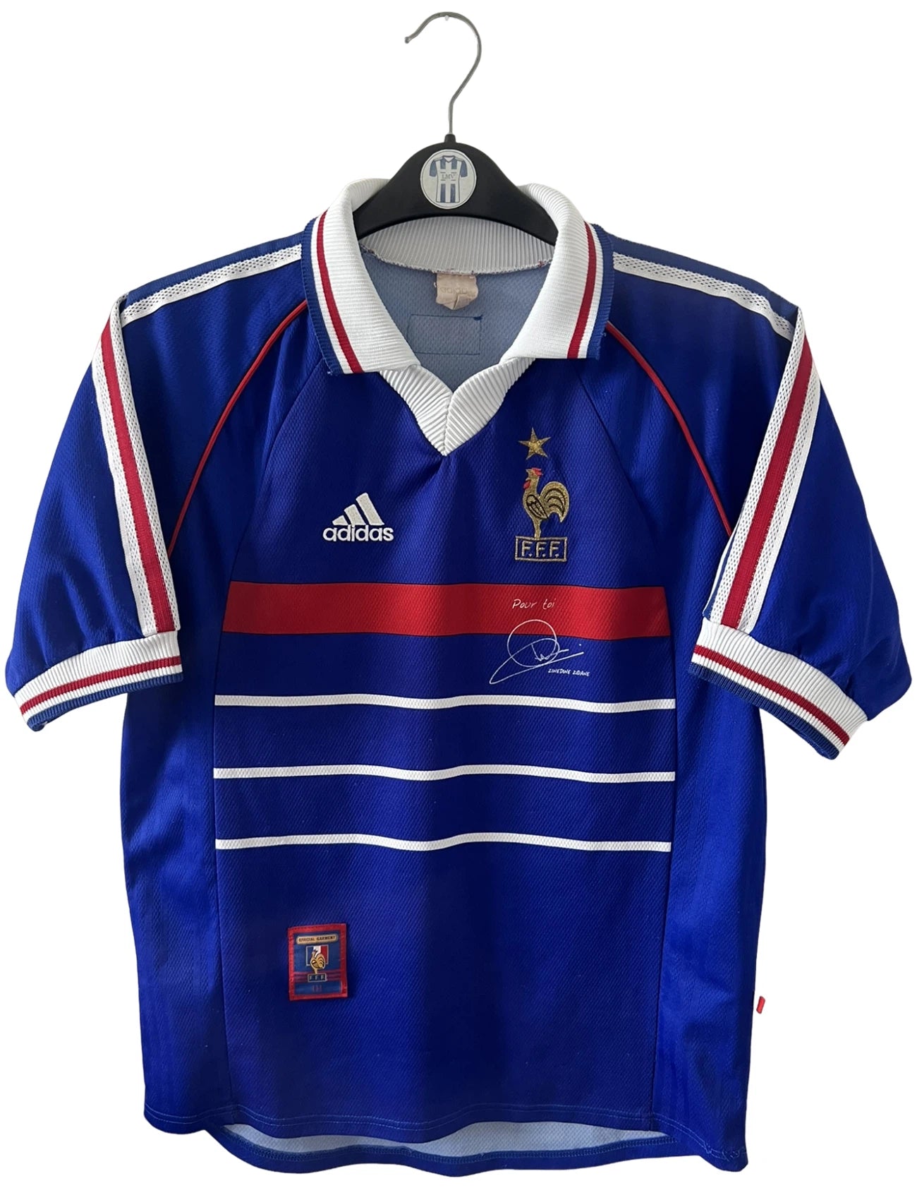 Maillot foot vintage domicile equipe de france 1998 bleu blanc et rouge. On peut retrouver l'équipementier adidas. Il s'agit d'un maillot authentique d'époque. Le maillot est floqué du numéro 10 Zinedine Zidane et comporte également sa signature avec la mention "pour toi Zinedine Zidane"