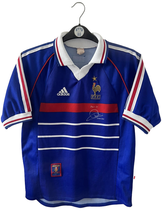 Maillot foot vintage domicile equipe de france 1998 bleu blanc et rouge. On peut retrouver l'équipementier adidas. Il s'agit d'un maillot authentique d'époque. Le maillot est floqué du numéro 10 Zinedine Zidane et comporte également sa signature avec la mention "pour toi Zinedine Zidane"