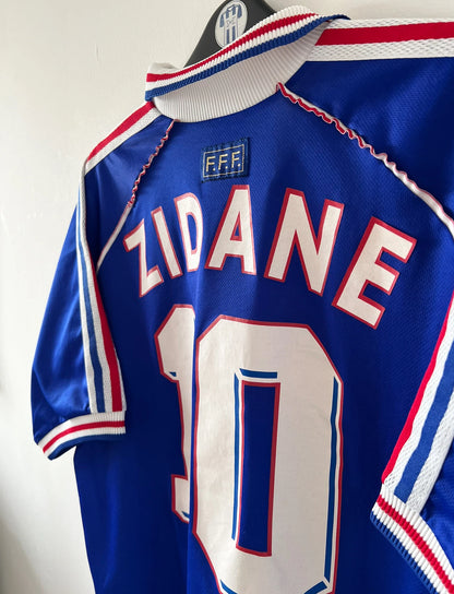 Maillot foot vintage domicile equipe de france 1998 bleu blanc et rouge. On peut retrouver l'équipementier adidas. Ils 'agit d'un maillot authentique d'époque floqué Zinedine Zidane