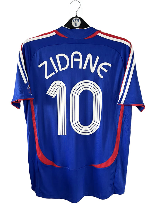 Maillot de foot vintage domicile bleu de l'équipe de france 2006. On peut retrouver l'équipementier adidas. Le maillot est floqué du numéro 10 Zinedine Zidane. Il s'agit d'un maillot authentique comportant l'étiquette 740126.