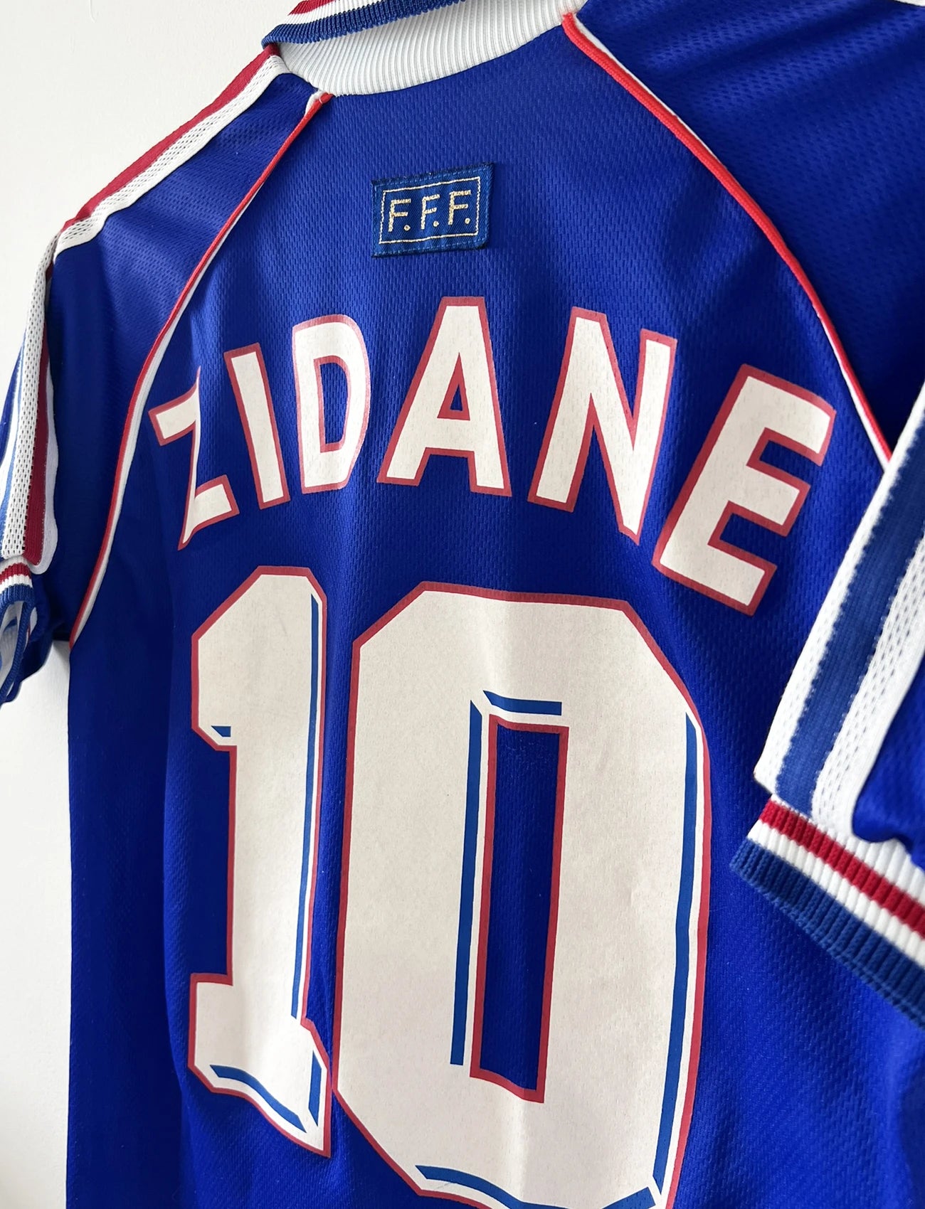 Maillot de foot vintage domicile bleu blanc et rouge de l'équipe de france lors de la coupe du monde 1998. On peut retrouver l'équipementier adidas. Le maillot est floqué du numéro 10 zinedine zidane. Il s'agit d'un maillot authentique d'époque.