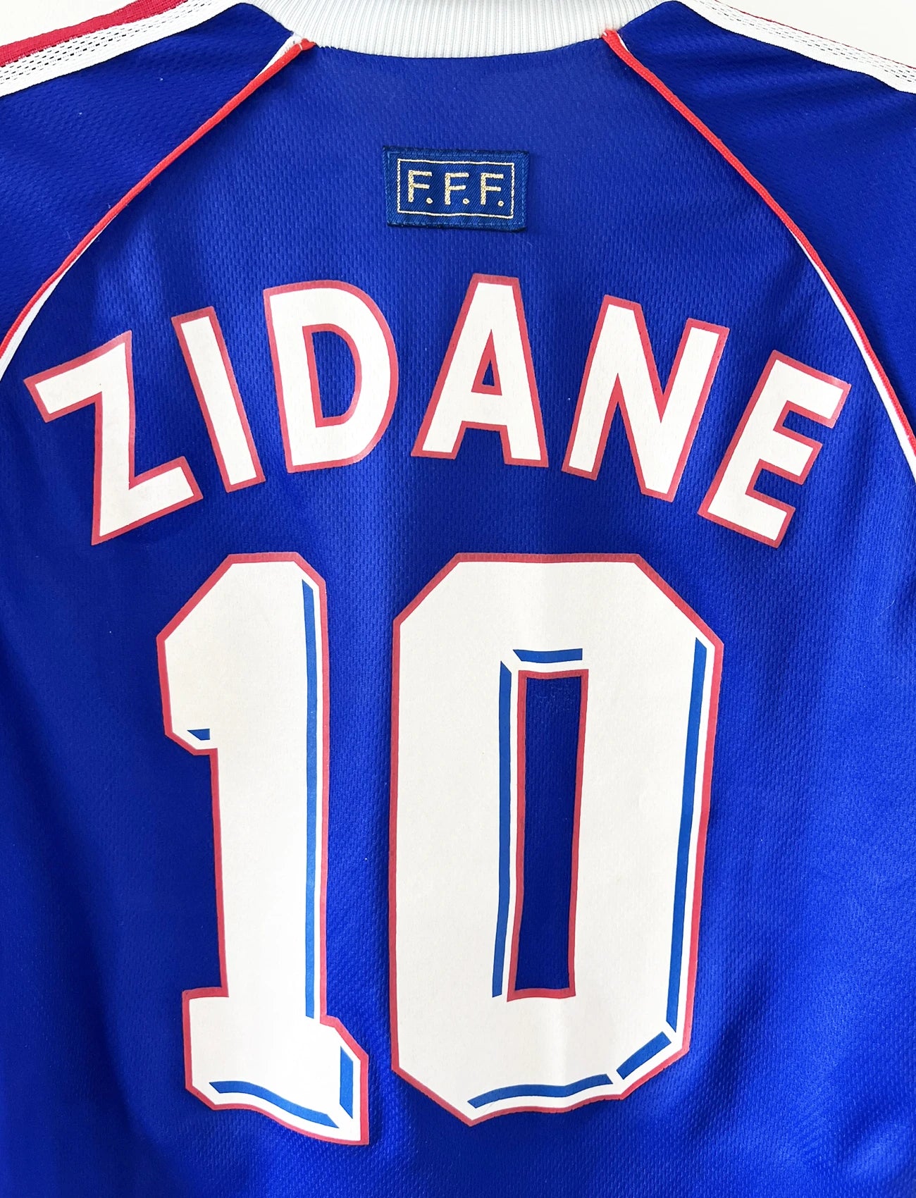 Maillot de foot vintage domicile bleu blanc et rouge de l'équipe de france lors de la coupe du monde 1998. On peut retrouver l'équipementier adidas. Le maillot est floqué du numéro 10 zinedine zidane. Il s'agit d'un maillot authentique d'époque.