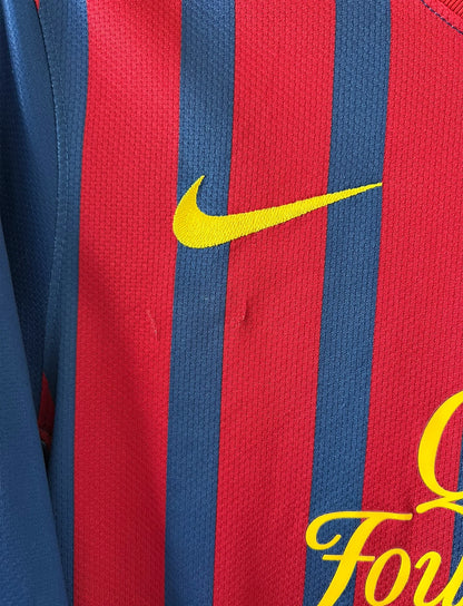 Maillot de foot vintage domicile rouge et bleu du FC Barcelone 2011/2012. On peut retrouver l'équipementier Nike et le sponsor Qatar Foundation. Le maillot est floqué du numéro 10 Lionel Messi. Il s'agit d'un maillot authentique d'époque
