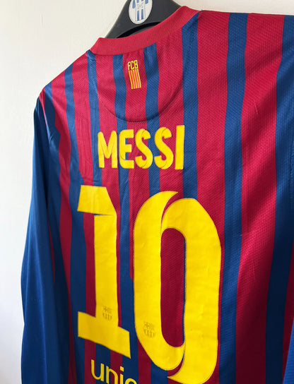 Maillot de foot vintage domicile rouge et bleu du FC Barcelone 2011/2012. On peut retrouver l'équipementier Nike et le sponsor Qatar Foundation. Le maillot est floqué du numéro 10 Lionel Messi. Il s'agit d'un maillot authentique d'époque