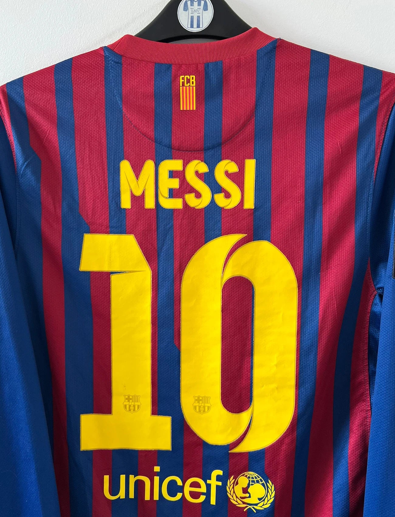 Maillot de foot vintage domicile rouge et bleu du FC Barcelone 2011/2012. On peut retrouver l'équipementier Nike et le sponsor Qatar Foundation. Le maillot est floqué du numéro 10 Lionel Messi. Il s'agit d'un maillot authentique d'époque