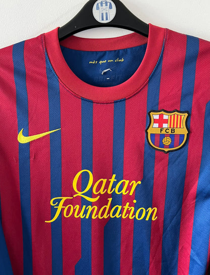 Maillot de foot vintage domicile rouge et bleu du FC Barcelone 2011/2012. On peut retrouver l'équipementier Nike et le sponsor Qatar Foundation. Le maillot est floqué du numéro 10 Lionel Messi. Il s'agit d'un maillot authentique d'époque