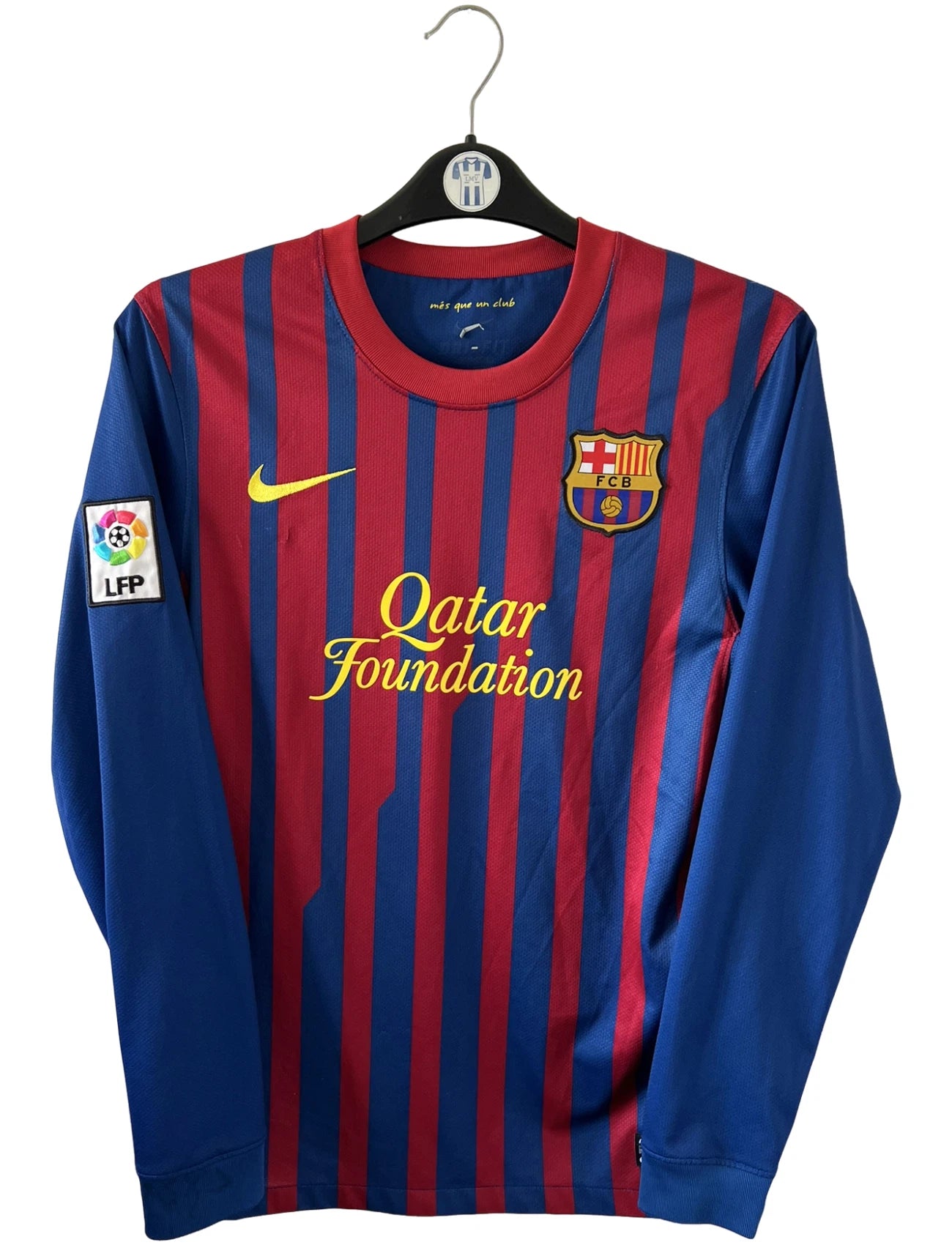 Maillot de foot vintage domicile rouge et bleu du FC Barcelone 2011/2012. On peut retrouver l'équipementier Nike et le sponsor Qatar Foundation. Le maillot est floqué du numéro 10 Lionel Messi. Il s'agit d'un maillot authentique d'époque