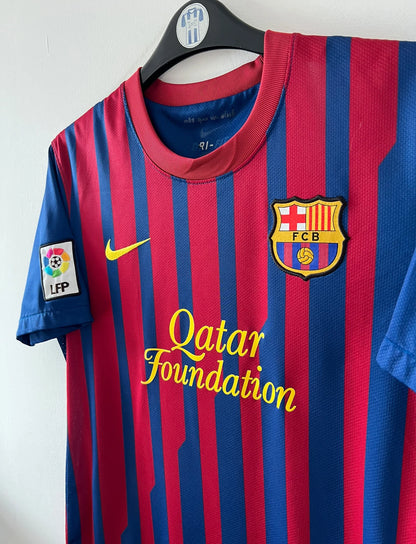 Maillot de foot vintage domicile rouge et bleu du FC Barcelone 2011/2012. On peut retrouver l'équipementier Nike et le sponsor Qatar Foundation. Le maillot est floqué du numéro 6 Xavi. Il s'agit d'un maillot authentique d'époque.