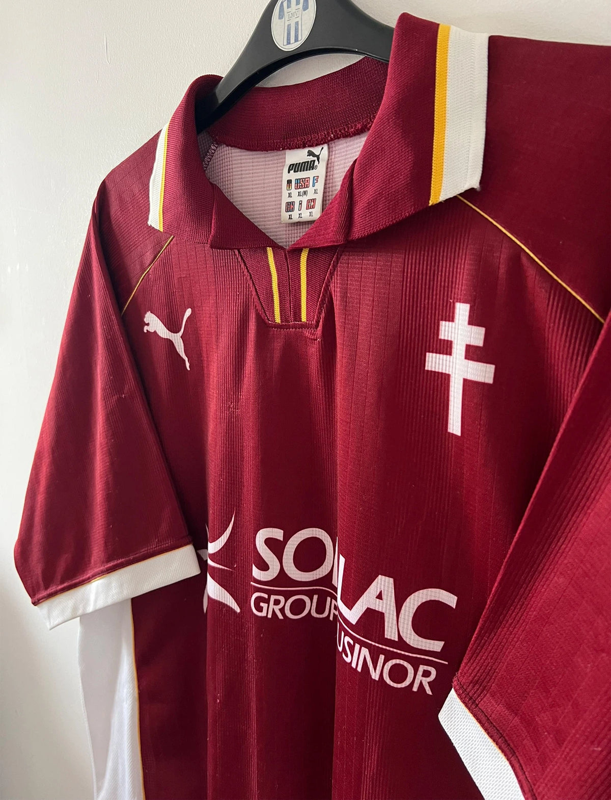 Maillot de foot vintage domicile rouge et blanc du FC Metz de la saison 1998/1999. On peut retrouver l'équipementier Puma et le sponsor Sollac. Le maillot est floqué du numéro 14 Geoffray Toyes. Il s'agit d'un maillot authentique d'époque.