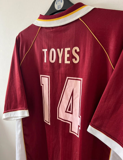 Maillot de foot vintage domicile rouge et blanc du FC Metz de la saison 1998/1999. On peut retrouver l'équipementier Puma et le sponsor Sollac. Le maillot est floqué du numéro 14 Geoffray Toyes. Il s'agit d'un maillot authentique d'époque.