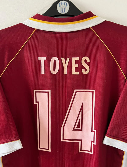 Maillot de foot vintage domicile rouge et blanc du FC Metz de la saison 1998/1999. On peut retrouver l'équipementier Puma et le sponsor Sollac. Le maillot est floqué du numéro 14 Geoffray Toyes. Il s'agit d'un maillot authentique d'époque.