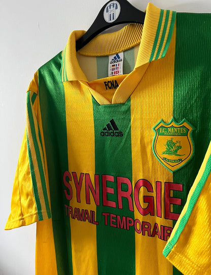 Maillot foot vintage domicile jaune et vert du FC Nantes 1998/2000. On peut retrouver l'équipementier Adidas et le sponsor Synergie. Il s'agit d'un maillot authentique d'époque.
