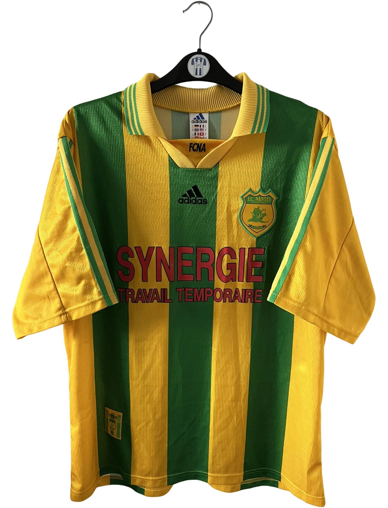 Maillot foot vintage domicile jaune et vert du FC Nantes 1998/2000. On peut retrouver l'équipementier Adidas et le sponsor Synergie. Il s'agit d'un maillot authentique d'époque.