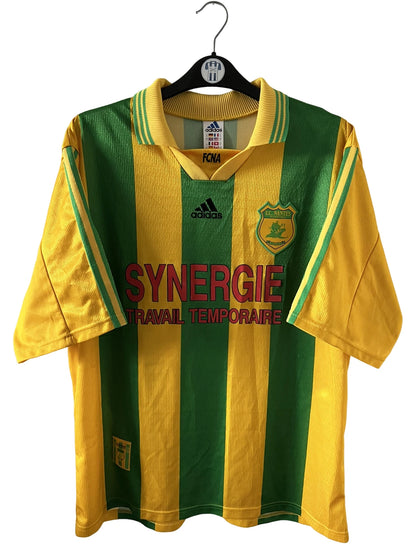 Maillot foot vintage domicile jaune et vert du FC Nantes 1998/2000. On peut retrouver l'équipementier Adidas et le sponsor Synergie. Il s'agit d'un maillot authentique d'époque.