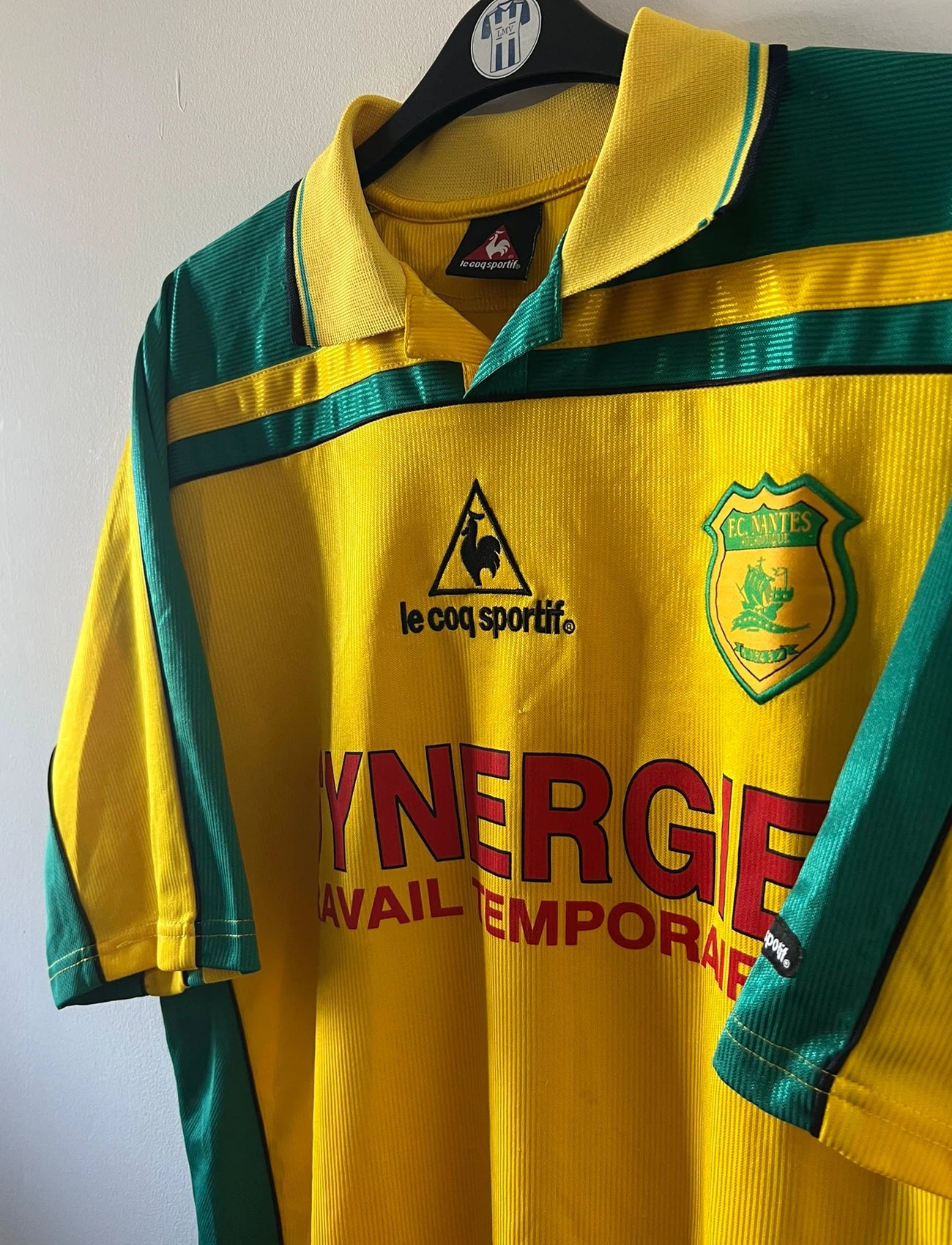 Maillot foot vintage domicile jaune et vert du FC Nantes 2001/2002. On peut retrouver l'équipementier Le Coq Sportif et le sponsor Synergie. Il s'agit d'un maillot authentique d'époque.