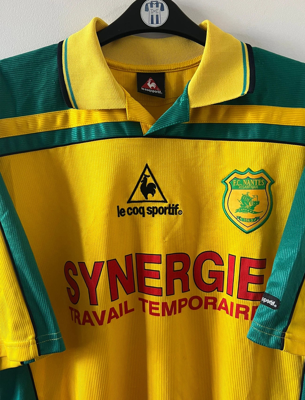 Maillot foot vintage domicile jaune et vert du FC Nantes 2001/2002. On peut retrouver l'équipementier Le Coq Sportif et le sponsor Synergie. Il s'agit d'un maillot authentique d'époque.