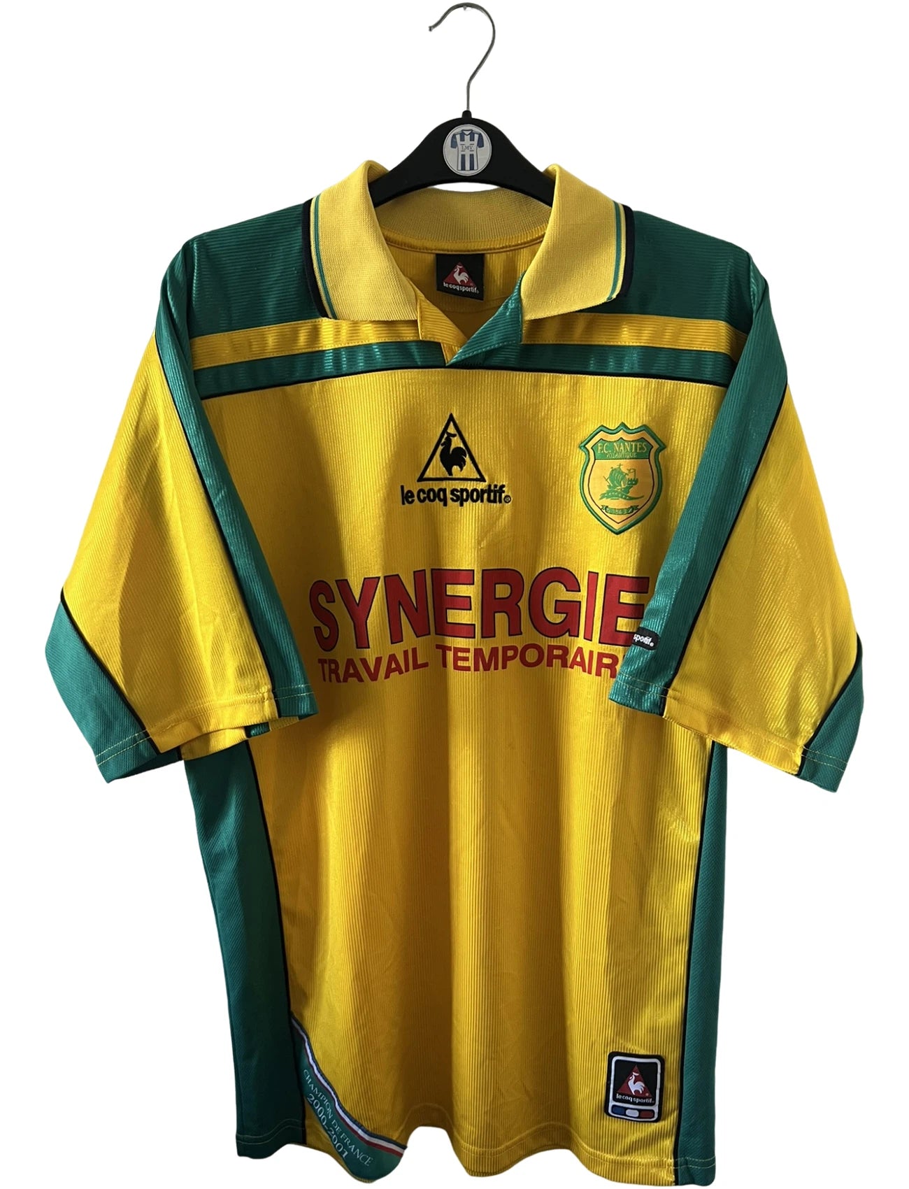 Maillot foot vintage domicile jaune et vert du FC Nantes 2001/2002. On peut retrouver l'équipementier Le Coq Sportif et le sponsor Synergie. Il s'agit d'un maillot authentique d'époque.